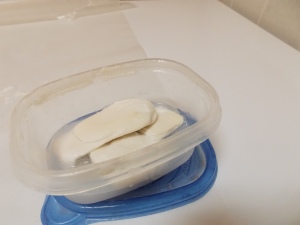 Soap slivers in a plastic container with about a half inch of water